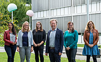 6 people of the International Office Team of UAS Kempten smile and pose in the university campus