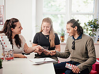 A counselor is advising two students in the office of the Landshut University of Applied Sciences
