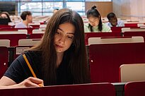 Student sitting at a desk writing something on a piece of paper