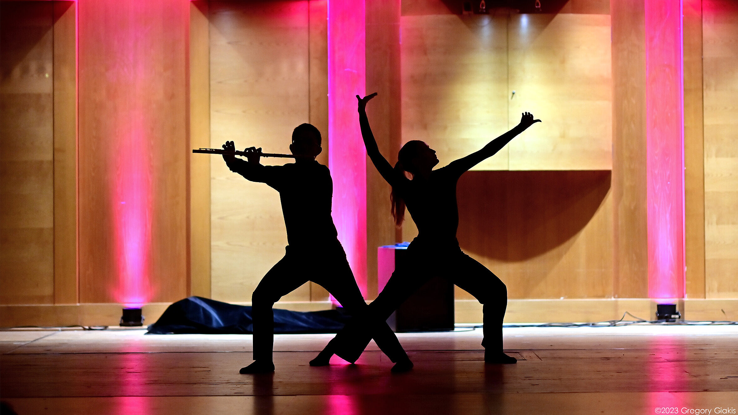 A man plays a brass instrument and a woman dances 