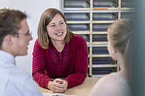 Three people sitting at a desk talking