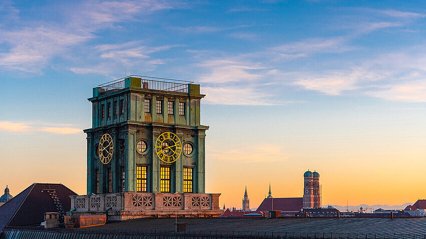 TUM Uhrenturm mit der Frauenkirche und der Skyline Münchens im Hintergrund