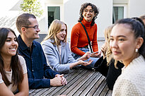 Eine Gruppe von Studierenden sitzt zusammen, sie lachen und reden