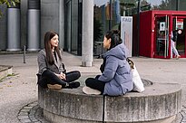 Two students sitting outside of a university building