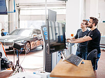 Two students are working on a computer in a car lab at the Landshut UAS