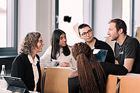 Eine Gruppe internationaler Studierende reden in einem Hörsaal