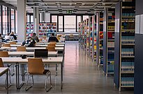 Library with tables and chairs on the left and book shelfs on the right