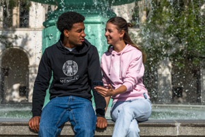 Two students sitting at the fountain having a conversation