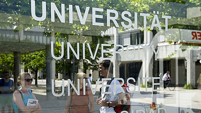 @ Uni Augsburg Studierende spiegeln sich in der Haltestelle an der Uni Augsburg