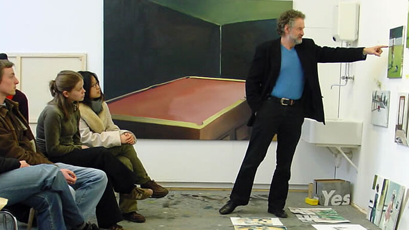 Unterricht @ Akademie der bildenden Künste Nürnberg Ein Dozent zeigt auf Bilder, Studierende schauen zu.