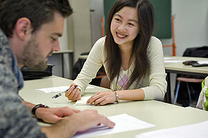 @ Uni Bayreuth A man and a woman sitting on opposite sides of a small table, working together