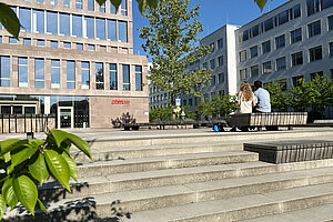 Students sitting on a bench in front of the library
