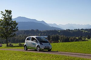 @ Kempten UAS Electric car drives in front of a mountain panorama
