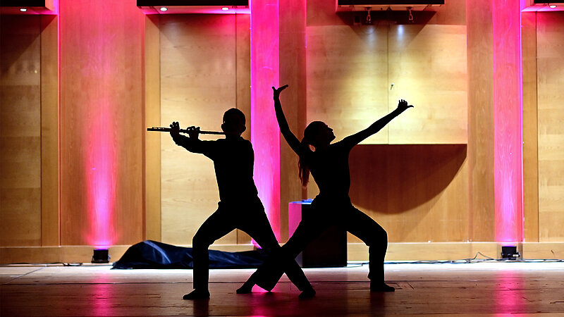 @ HMTM Ein Mann spielt ein Blasinstrument während eine Frau dazu tanzt