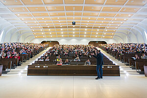 © LMU Blick vom Podium: Der Hörsaal der LMU im Biomedizinischen Zentrum ist voller Studenten. Ein Dozent hält eine Vorlesung.