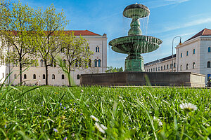 © LMU Der Brunnen am Hauptgebäude der LMU in Betrieb an einem sonnigen grünen Tag