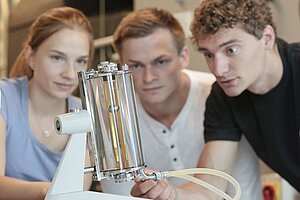 A group of students focusing on a piece of modern technology