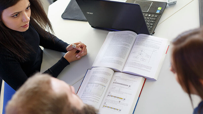 Three students are discussing a book.