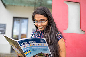 © Benjamin Herges A female student reads the university magazine uni.vers