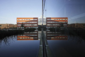 © LMU A brick-colored building reflected on a mirror surface