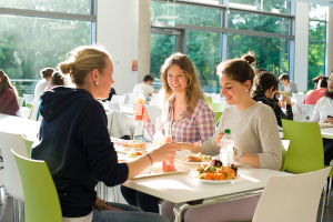 @ Uni Bayreuth Three women dine together in the university's sunlight-filled mensa