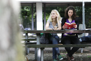 Entspannung auf dem Campus Zwei Studentinnen entspannen sich auf einer Bank auf dem Campus.