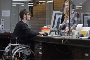 Ein Studierender im Rollstuhl an einerm Infodesk